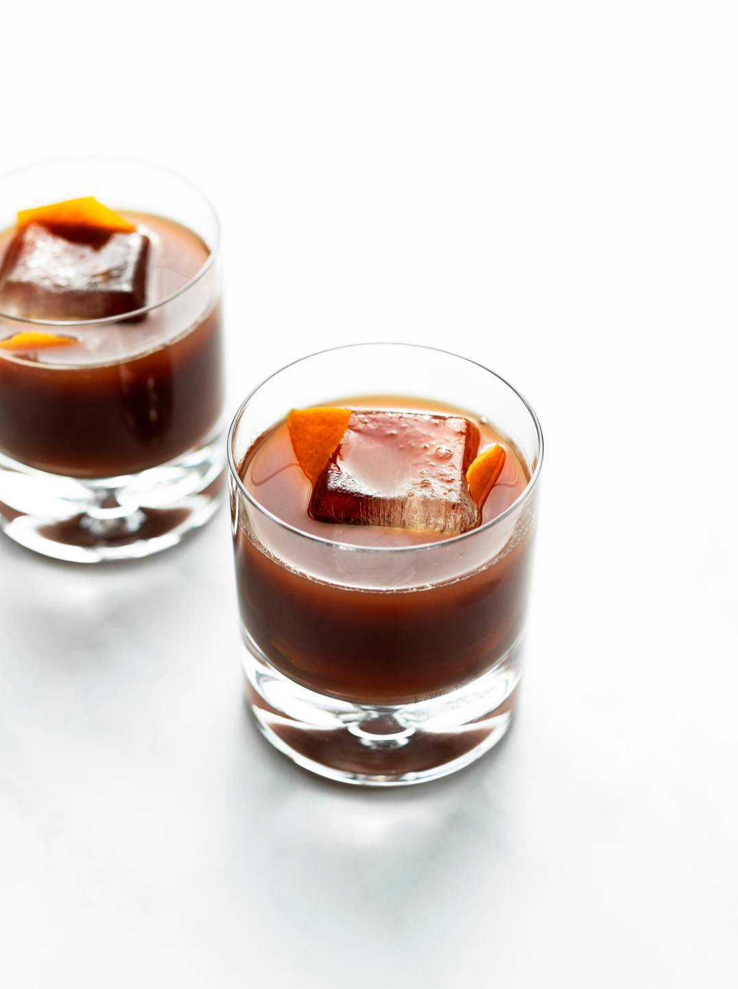 Two tumblers filled with rich dark brown juice over ice.