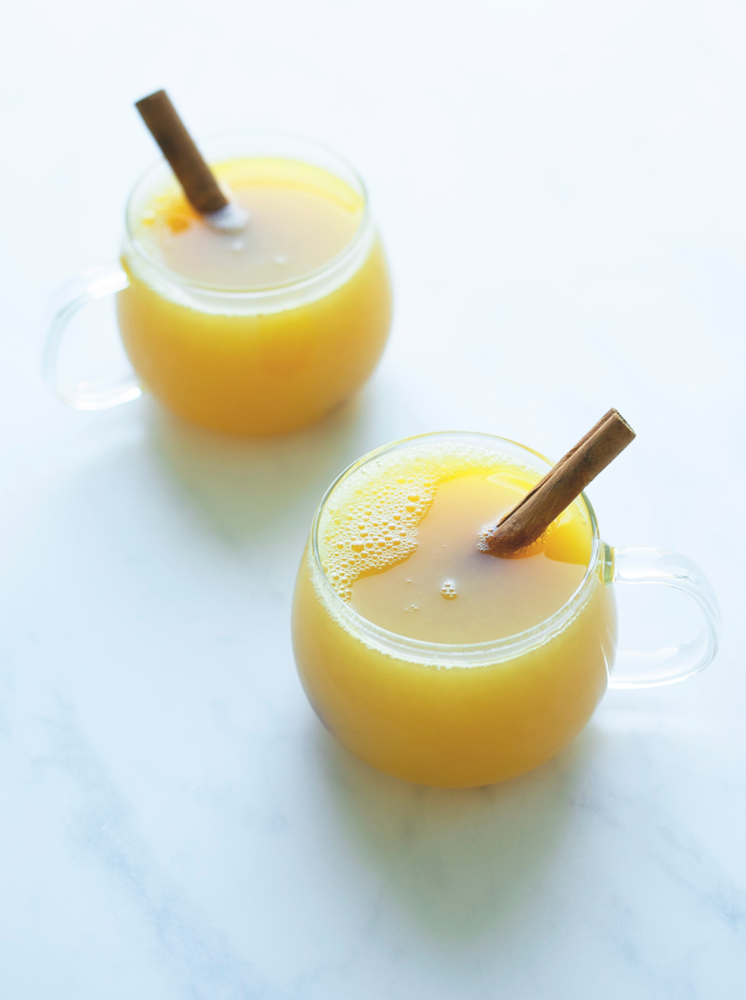 Two glass mugs filled with mock toddy and garnished with cinnamon stick