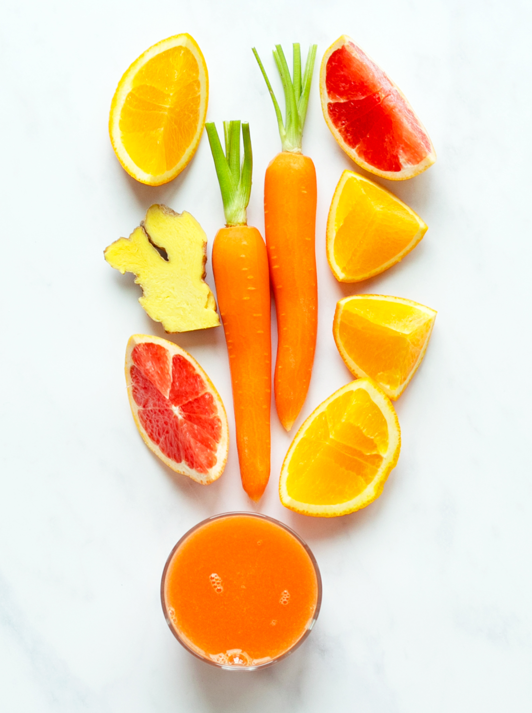 a glass of orange juice with carrots orange grapefruit and ginger
