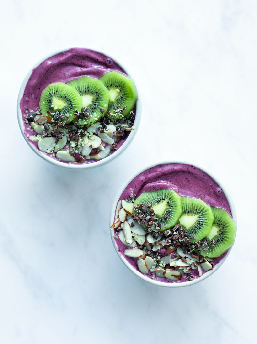 2 berry vitality smoothie bowls on a marble surface