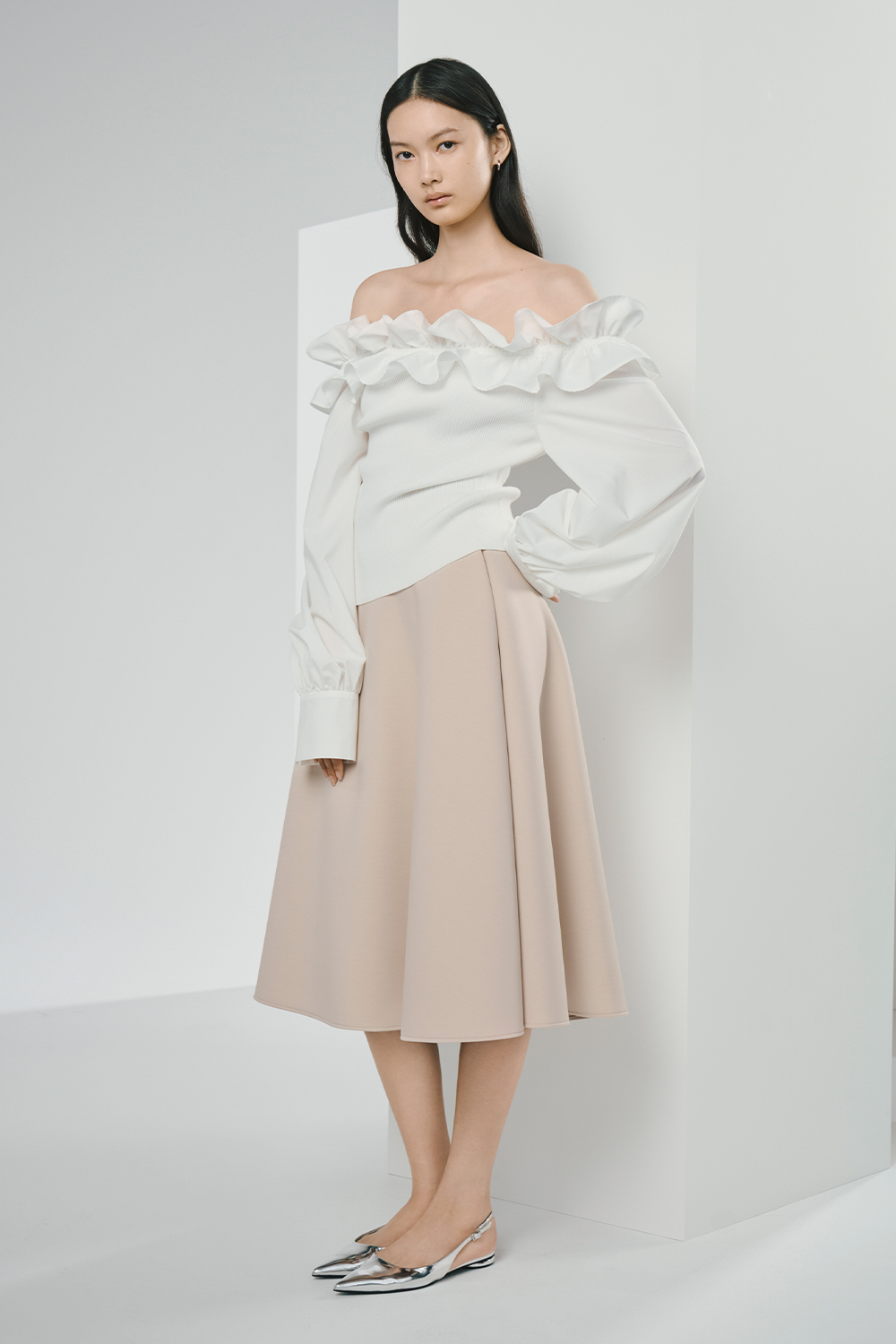 Model is wearing a white top and a pink skirt.