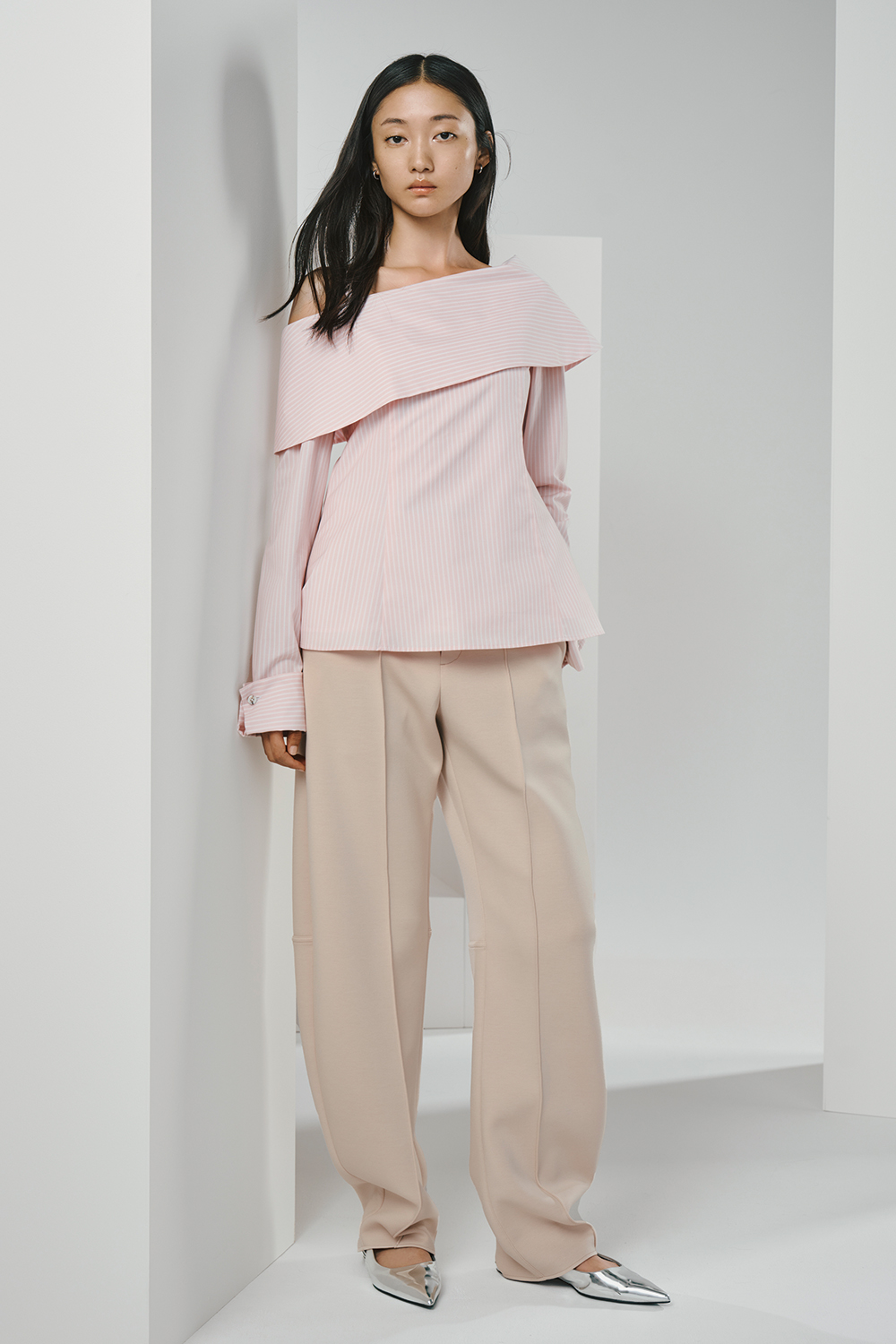 Model is wearing a pink top and beige pants.