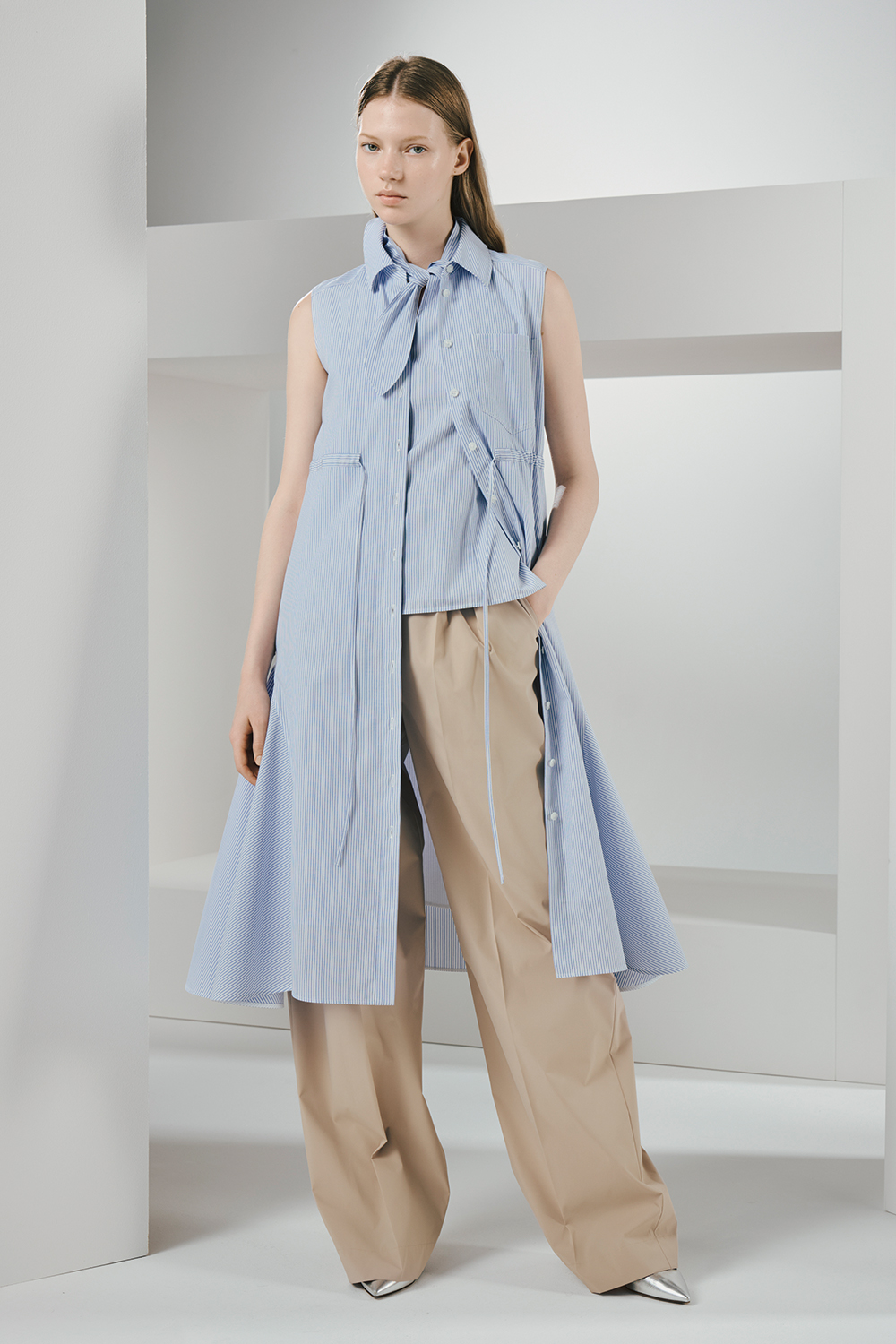 Model is wearing a blue dress and beige pants.