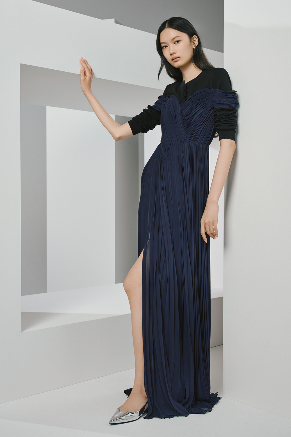 Model is wearing a navy dress over a black cardigan.