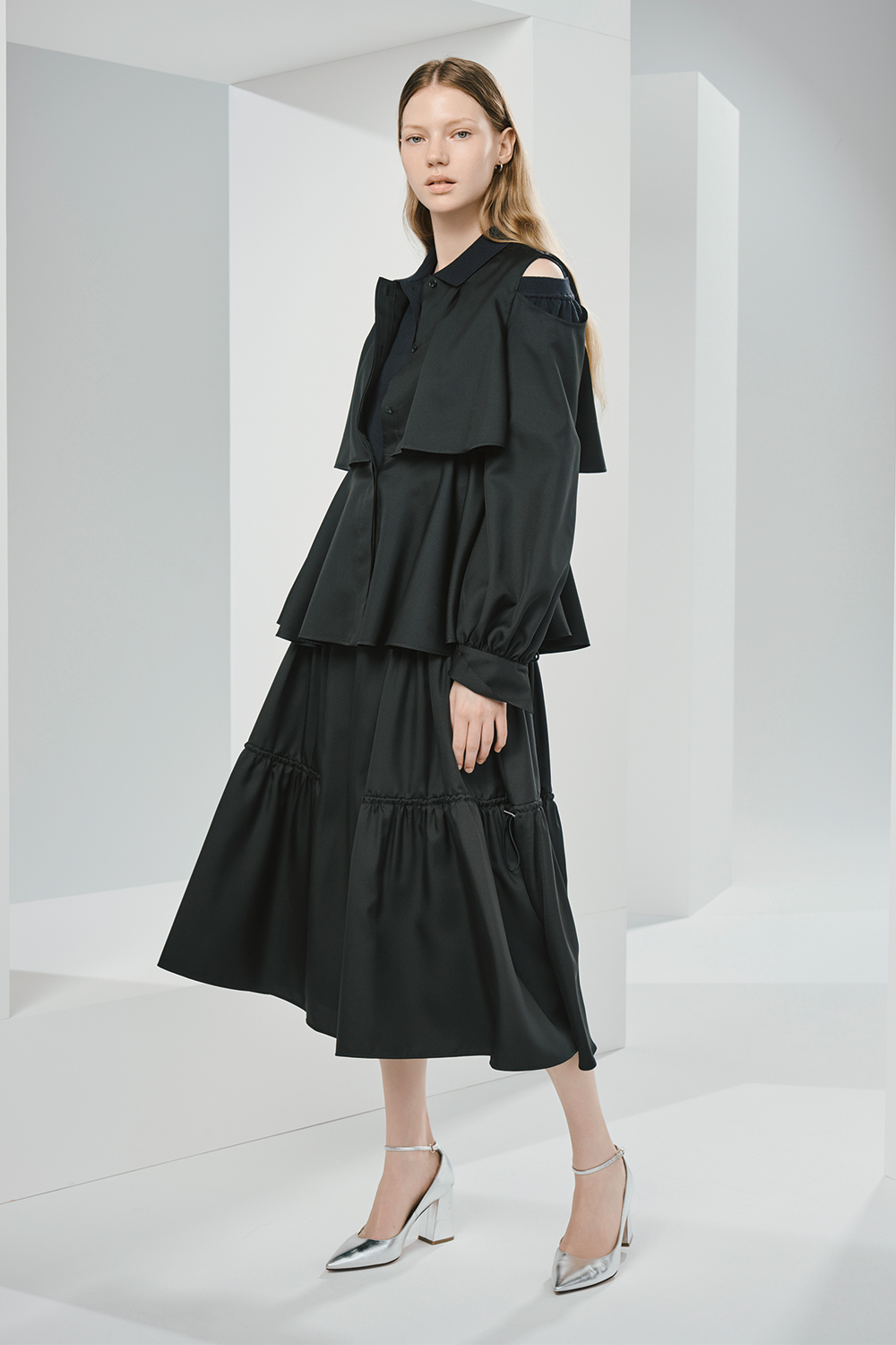 Model is wearing a black top over a black dress.