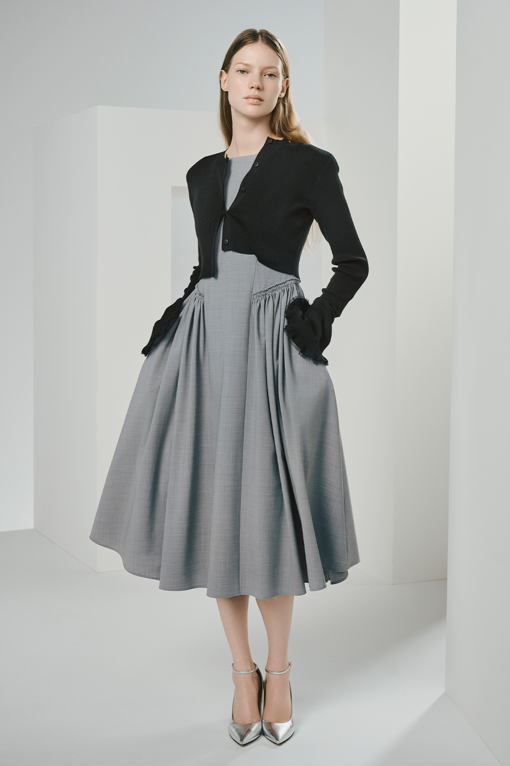 Model is wearing a black cardigan over a gray dress.