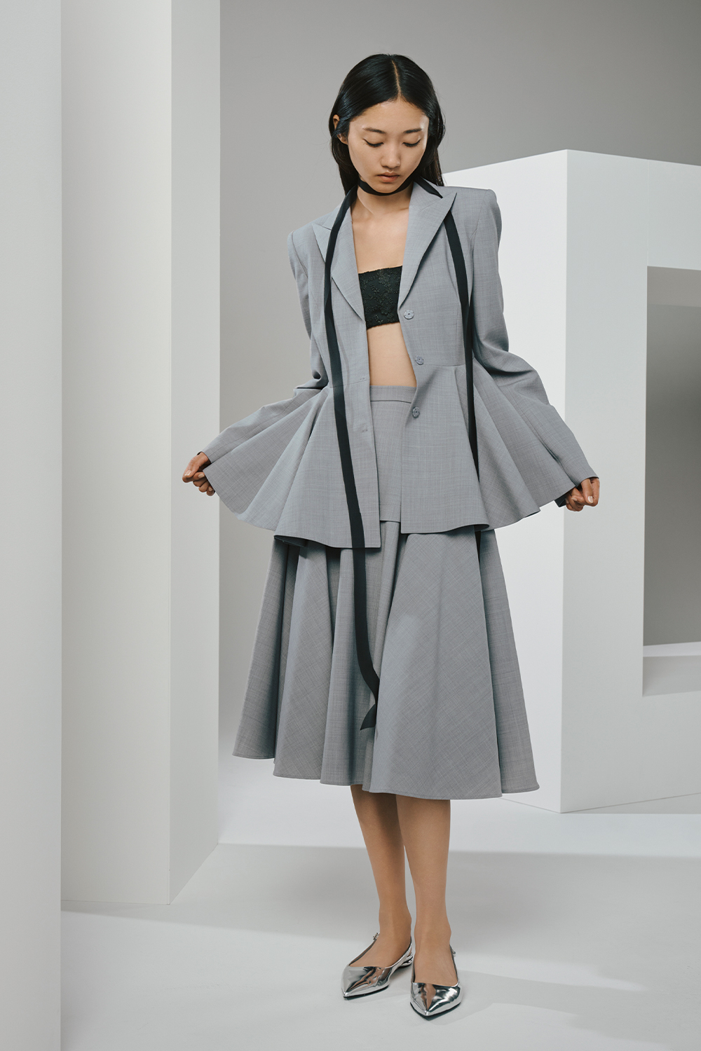 Model is wearing a gray jacket and a matching skirt.