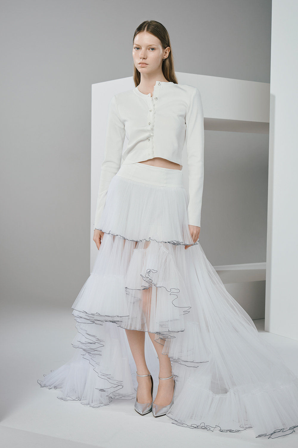 Model is wearing a white cardigan and a white lace skirt.