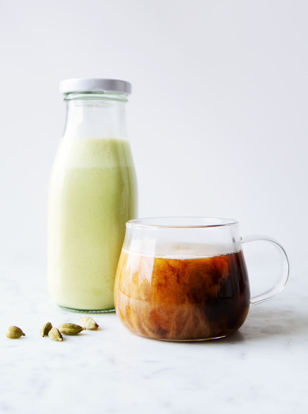 a bottle of pumpkin seed creamer with a glass cup of coffee
