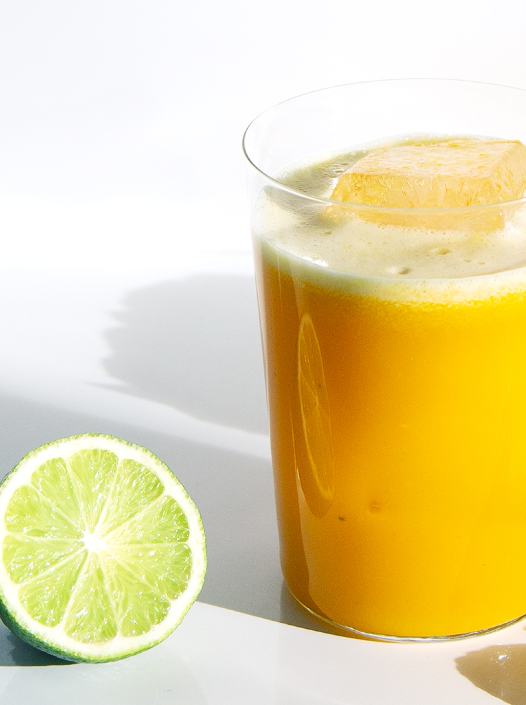 a glass of pineapple soother and a lime