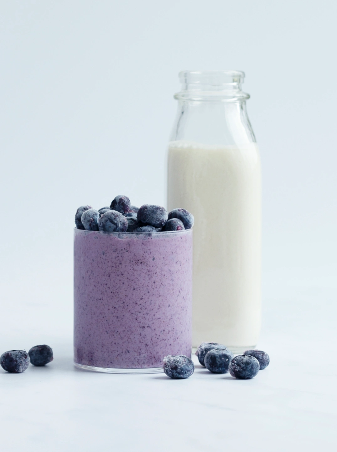 a glass of purple peanut berry smoothie with fresh blueberries
