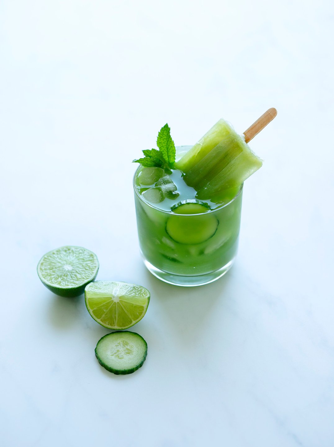 a glass of juice with a Cucumber Mint + Lime Popsicle