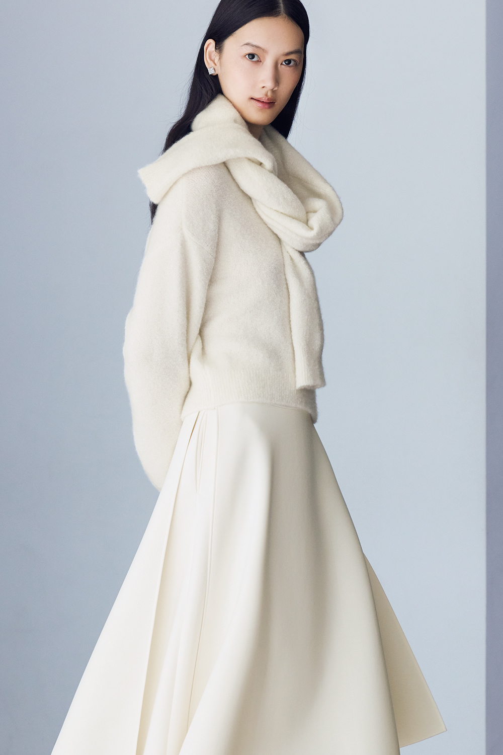 Model is wearing a white sweater and skirt.