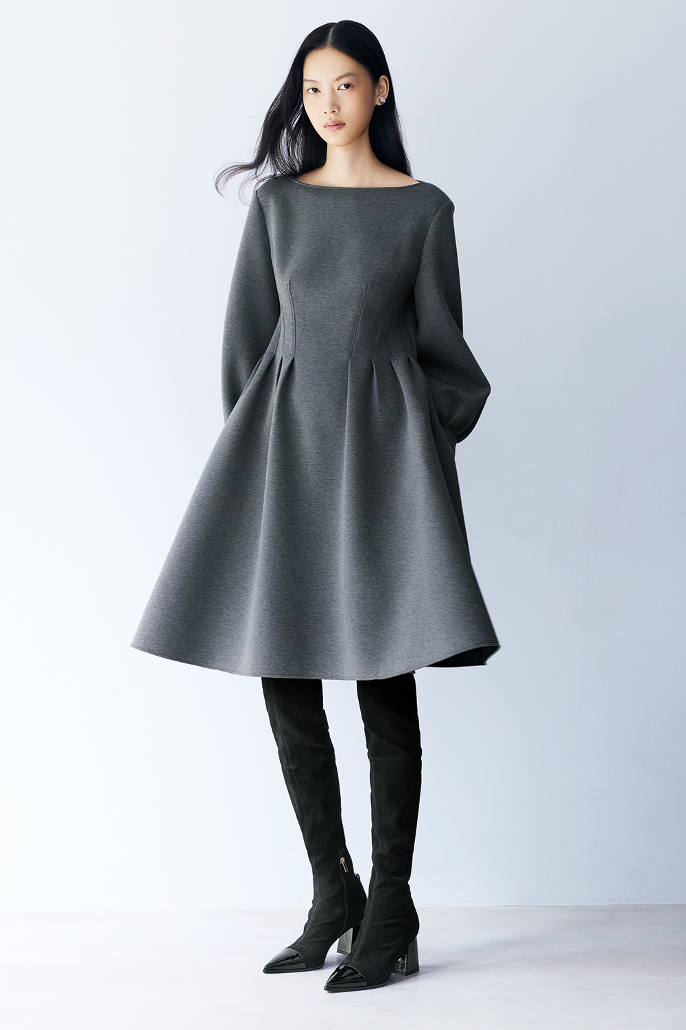 Model is wearing a grey dress and black boots.