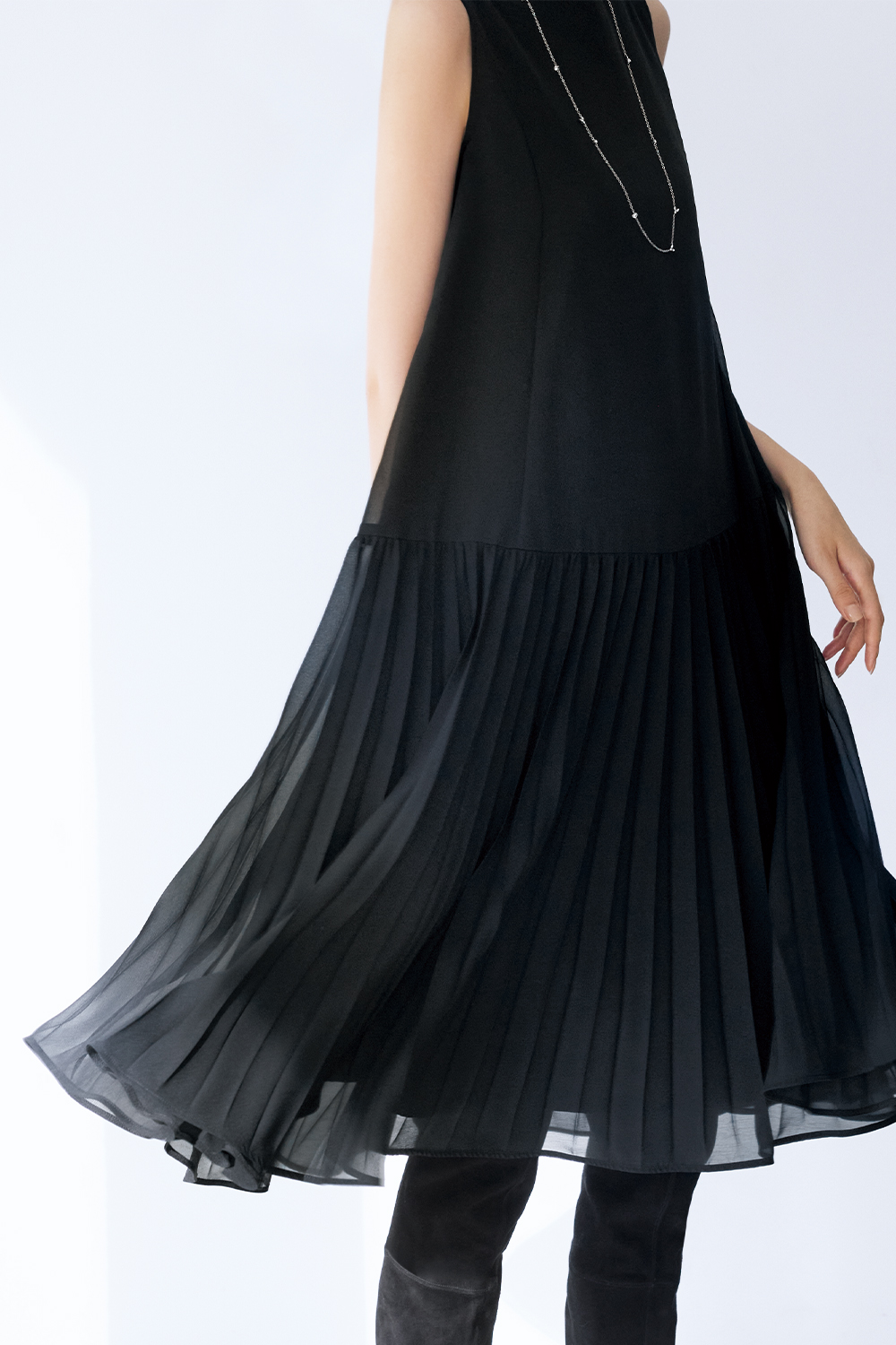 Model is wearing a black dress and a silver necklace.