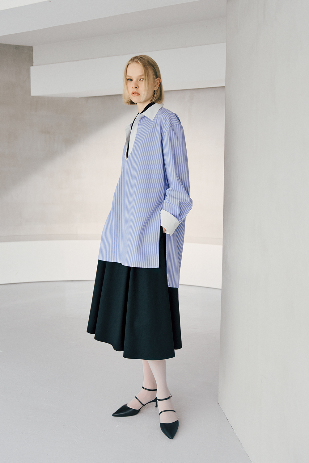 The model is wearing a blue and white striped top and a black skirt.