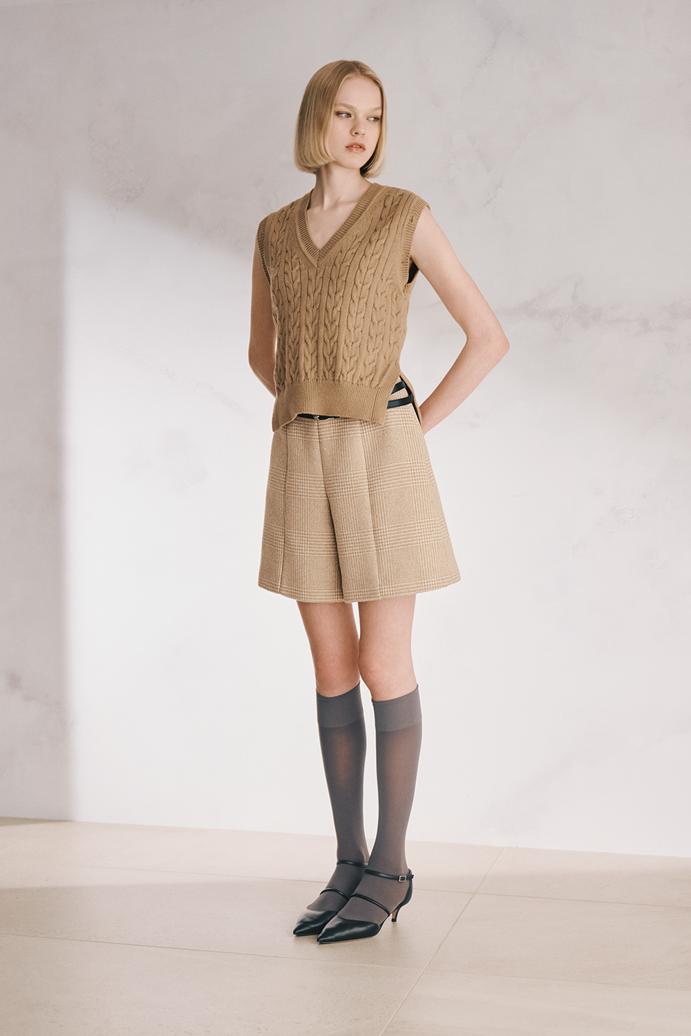 The model is wearing a beige short-sleeve top and shorts set.