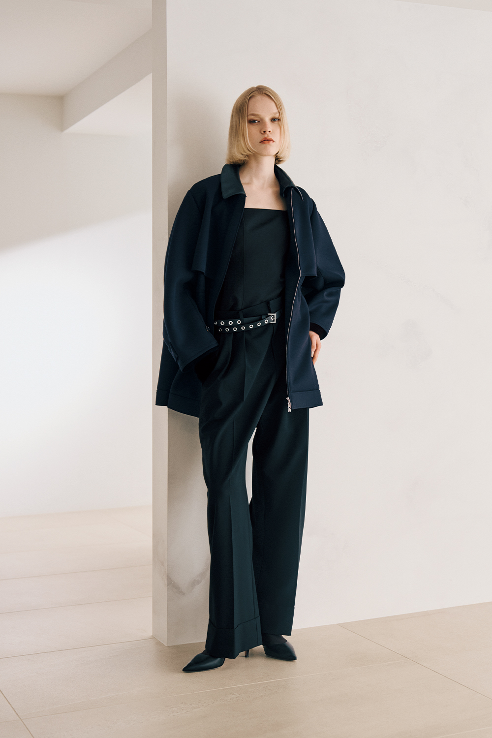 The model is wearing a black jacket and black pants.