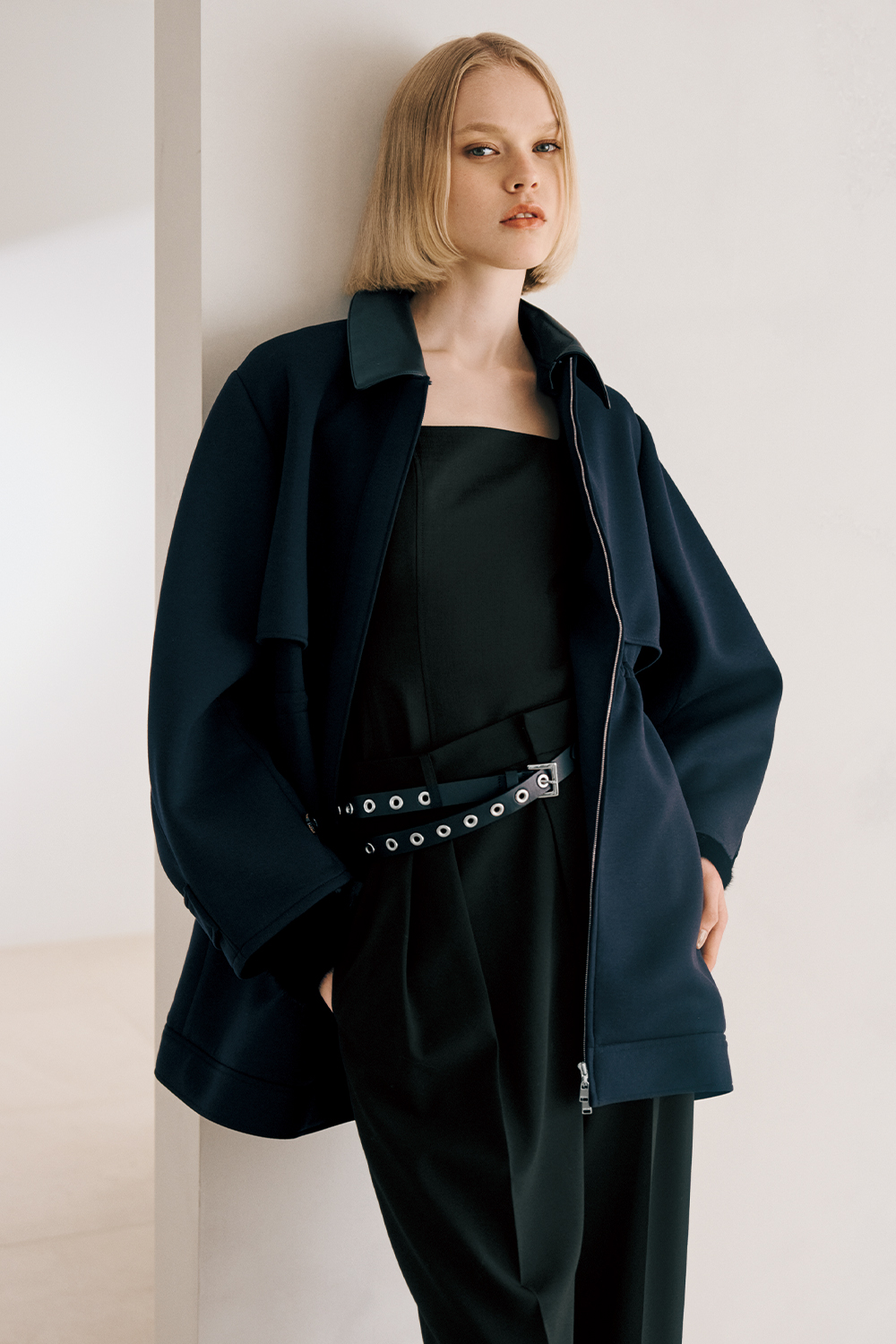 The model is wearing a black jacket and black pants.