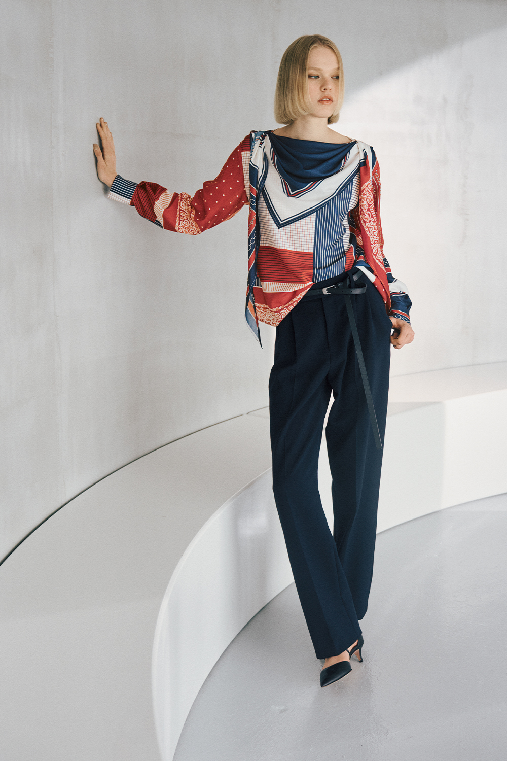 The model is wearing a blue and white patterned top and navy pants.