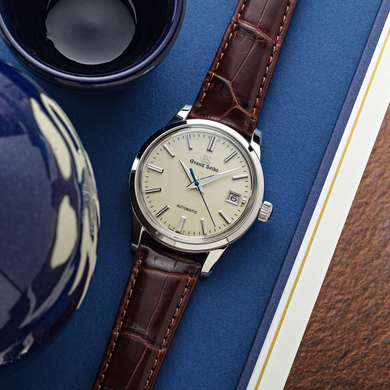 A classic ivory dial dress watch with a blue second hand on a brown strap. 