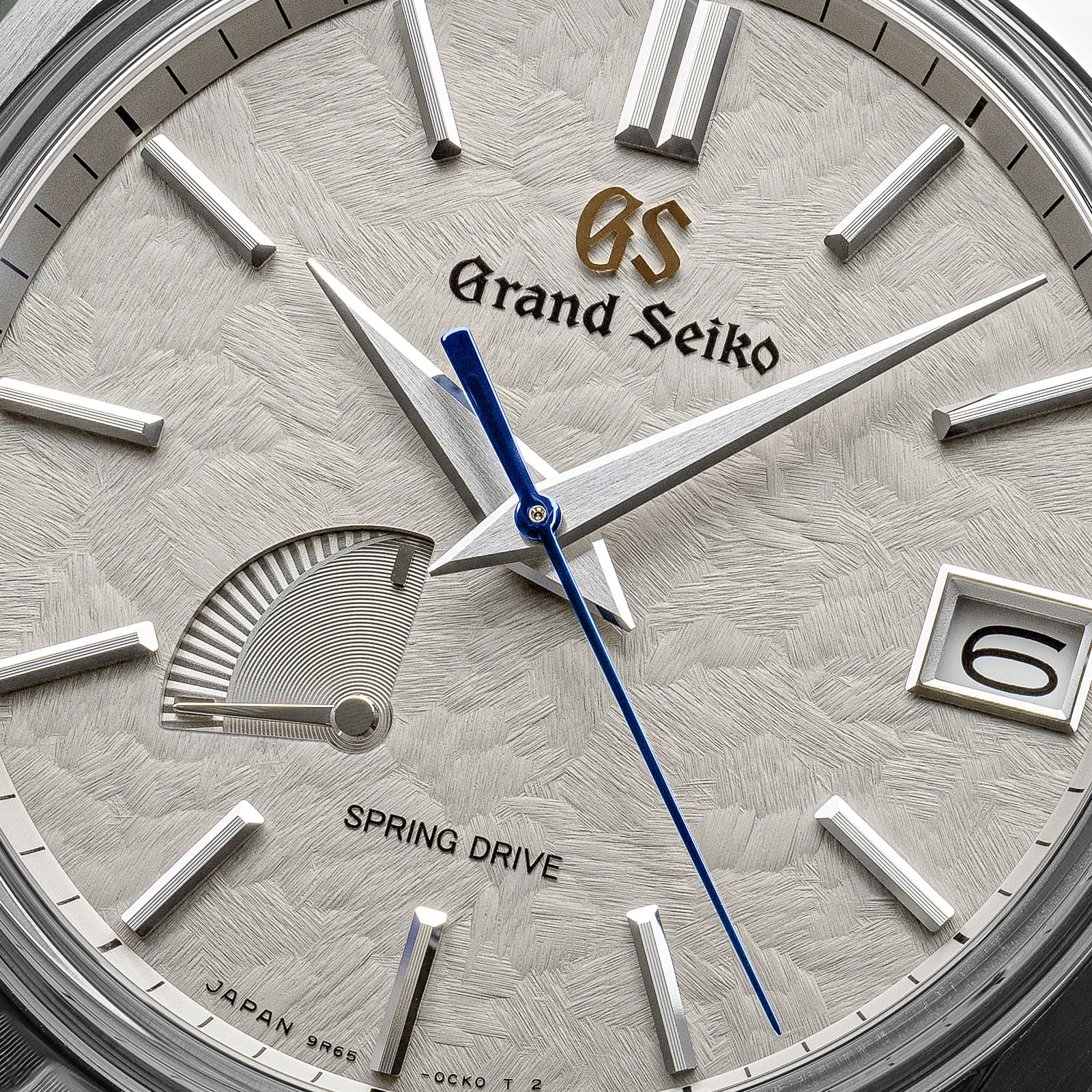 Grey textured dial with blue and gold-tone accents. 