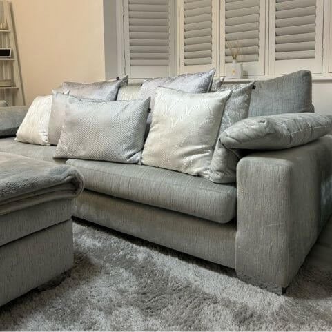A dark grey sofa decorated with a tonal arrangement of light grey, dark grey and silver scatter cushions.