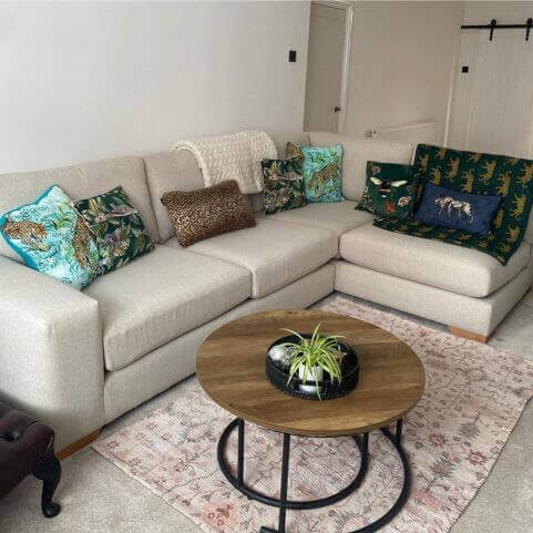 A light grey corner sofa decorated with a variety of bright, exotic and animal-print cushions.