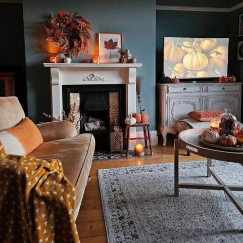 An autumnal living room decorated with a brown sofa, a monochrome rug, an amber dip dye style cushion, and various autumnal accessories.