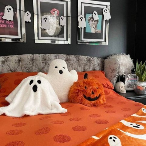 Three Halloween themed plush toys arranged on a bed with a tufted pumpkin duvet cover set and a coordinating throw with a ghost design.