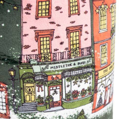 A closeup on the fabric and pattern of a Christmas door stop with a printed festive town design.