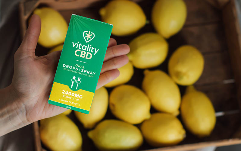 CBD oil in lemon flavour next to fresh lemons.