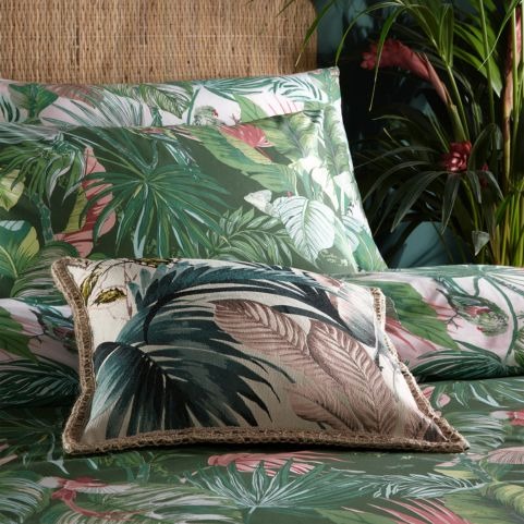 palm printed cushion on top of palm tree printed duvet set in bed