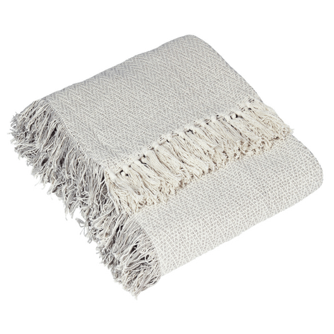 a folded up cotton throw with fringing and tasselling in a light feather colour.