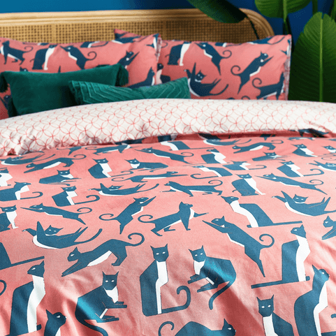 the Kitta cat watermelon duvet cover set on a bed, styled with green velvet cushions