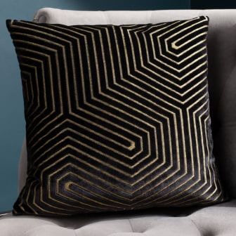 A black luxe-style cushion with a cut velvet geometric design and opulent gold detailing.