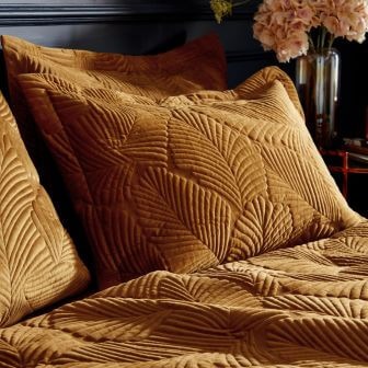 A luxe duvet cover set with a quilted velvet design of large leaves in a premium gold tone.