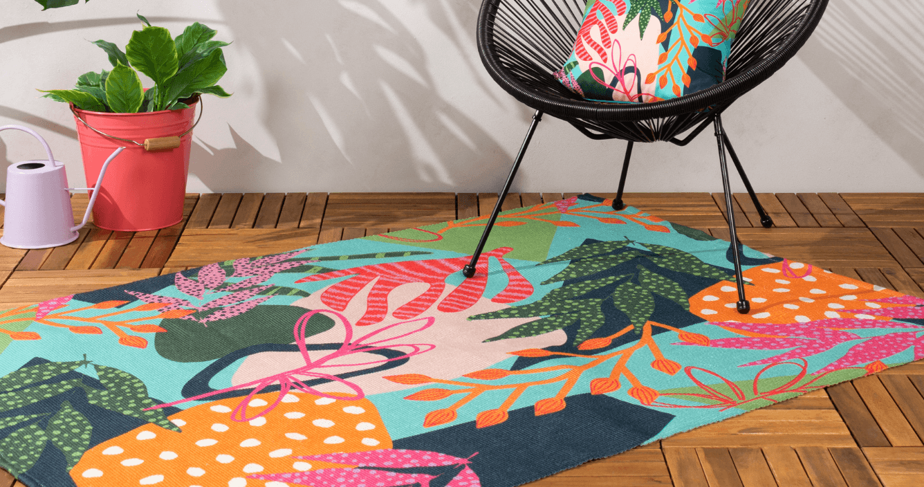 a multicolour floral outdoor rug on wooden decking with chair on top