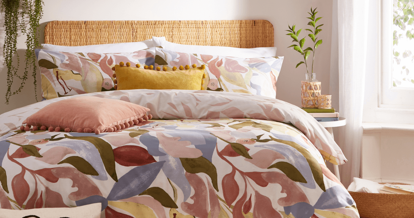 a multicoloured floral printed duvet cover set, with blush pink and yellow decorative cushions.