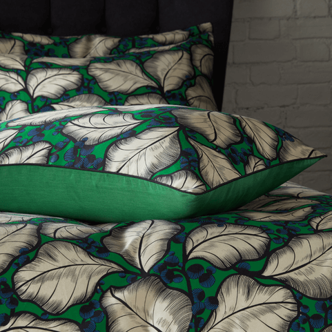 a bed with a green leafy pattern bedding on it. there is a pillow with the same green pattern on it on top of the bedding