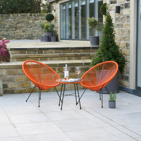 a steel orange bistro set consisting of two chairs and a side table