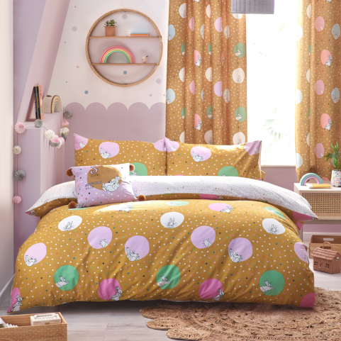 A bedroom with ochre Peter Rabbit bedding on a double bed, designed with pastel lilac and mint polka dots, and confetti. There is a matching pair of curtains hanging in the background.
