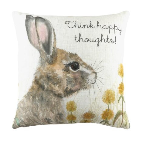 a white cushion printed with a watercolour illustration of a hare sitting in a field of yellow dandelions, with printed text that says 
