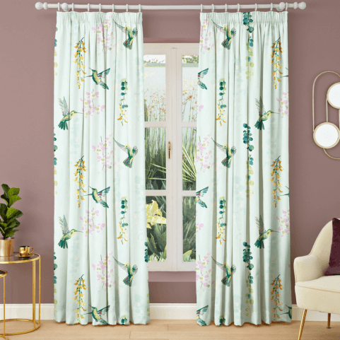 Duck egg coloured made to measure curtains printed with illustrations of hummingbirds and flowers, hanging in a purple painted room.