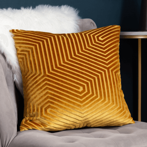 a geometric pattern cut velvet cushion in gold.