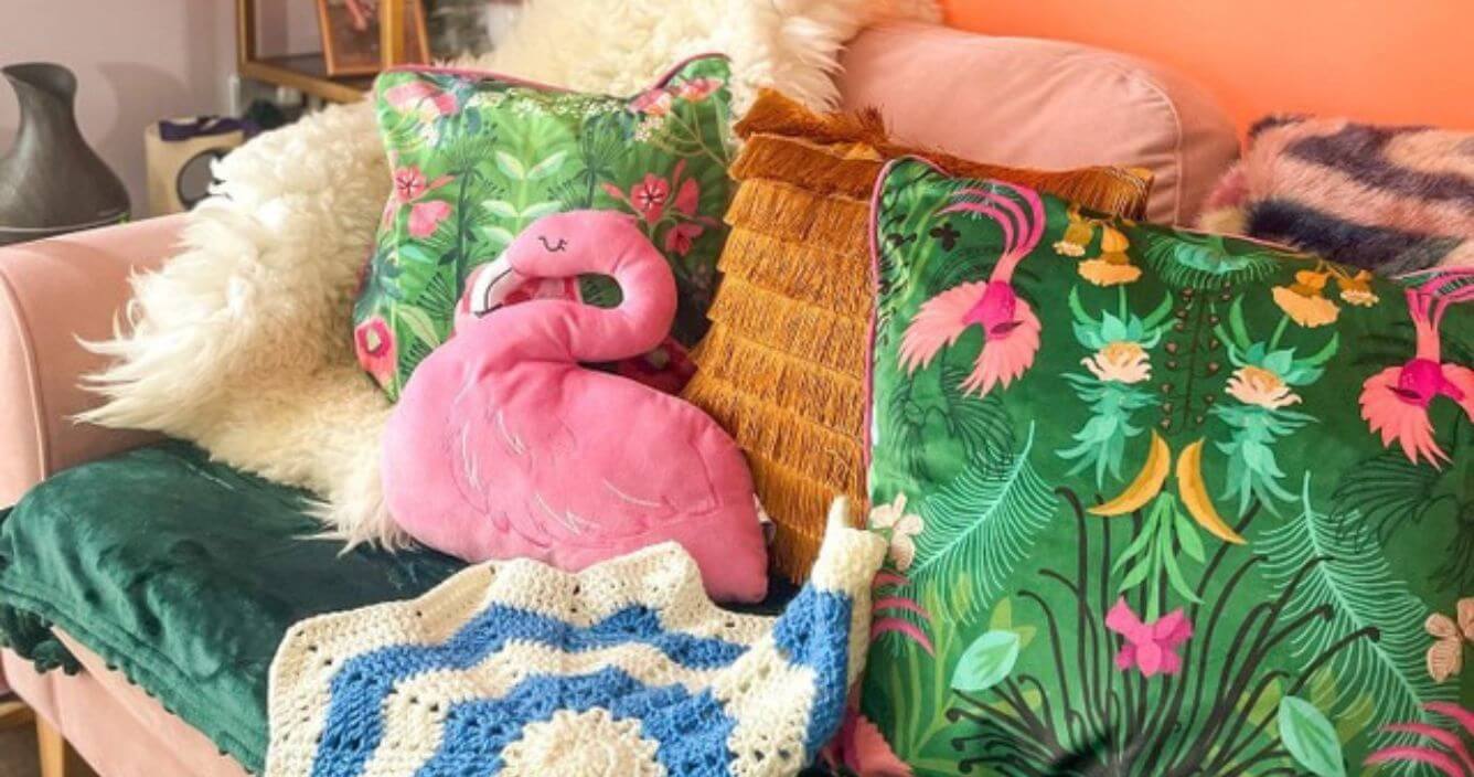 A selection of dopamine decor, including a vibrant floral cushion, interesting textures and a novelty flamingo plushie.