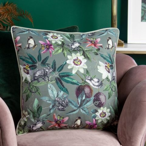 A floral pattern cushion in sage green on a lilac velvet chair.