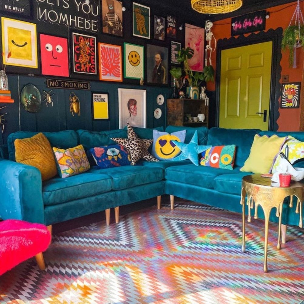 A maximalist living room with loads of colourful cushions on a teal velvet sofa. 