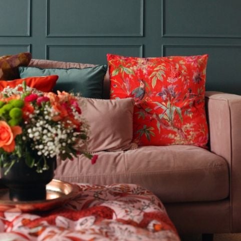 Orange, green and pink sofa cushions displayed on a coordinating red sofa.