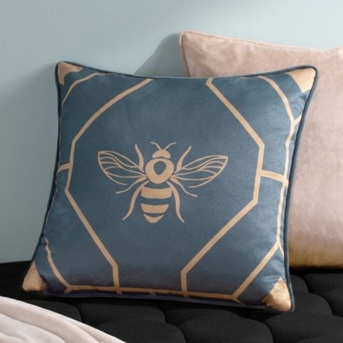 A french blue cushion featuring a geometric bee design, matched with a black sofa.